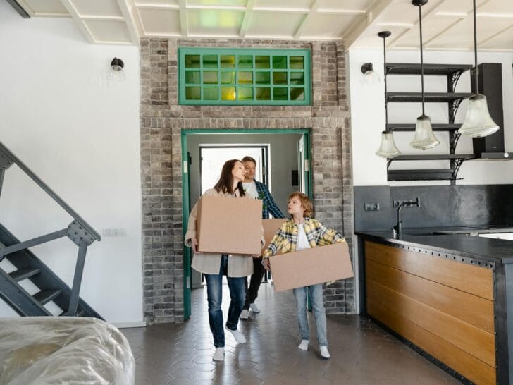Couple and their kid carrying moving boxes and talking about community integration for homeschoolers after a move.